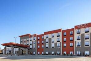 A multi-story hotel with a red and grey facade, multiple windows, and a clear sky.