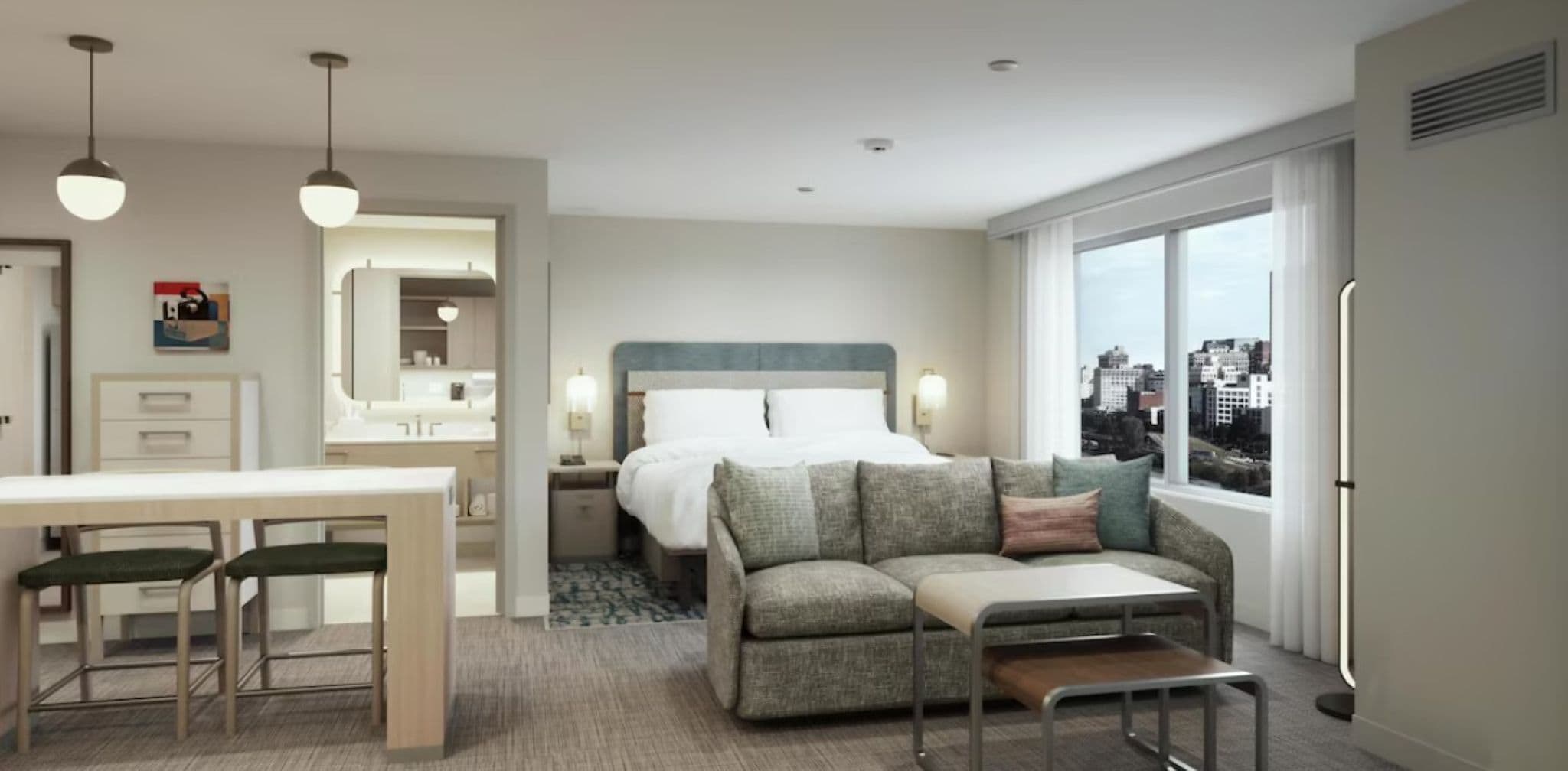 Ein Hotelzimmer mit Bett, einer Couch, einem Esstisch mit Stühlen, einem Spiegel und einem Fenster mit Blick auf die Stadt.