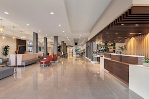 Un moderno vestíbulo de hotel con una recepción, una zona de estar y un pasillo que conduce a otras habitaciones.