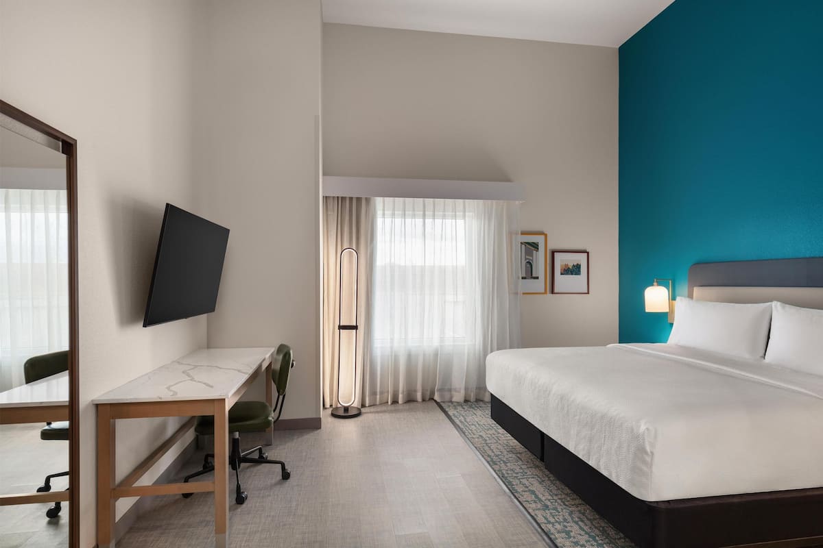 Ein Hotelzimmer mit Bett, Schreibtisch, Stuhl und Fernseher.