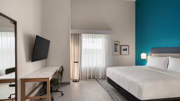 Una habitación de hotel con cama, escritorio, silla y televisor.