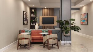 A modern living room with a sofa, two chairs, a TV, and decorative items. - Homewood Suites By Hilton Wichita Airport (Wichita)