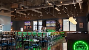 A bar/lounge area with seating, a neon sign, and sports screens. - Homewood Suites By Hilton Wichita Airport (Wichita)
