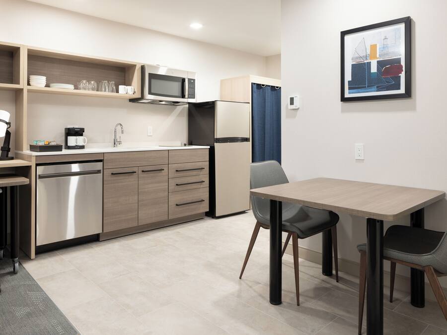 A modern kitchen with a microwave, refrigerator, and a dining area with a table and chairs.