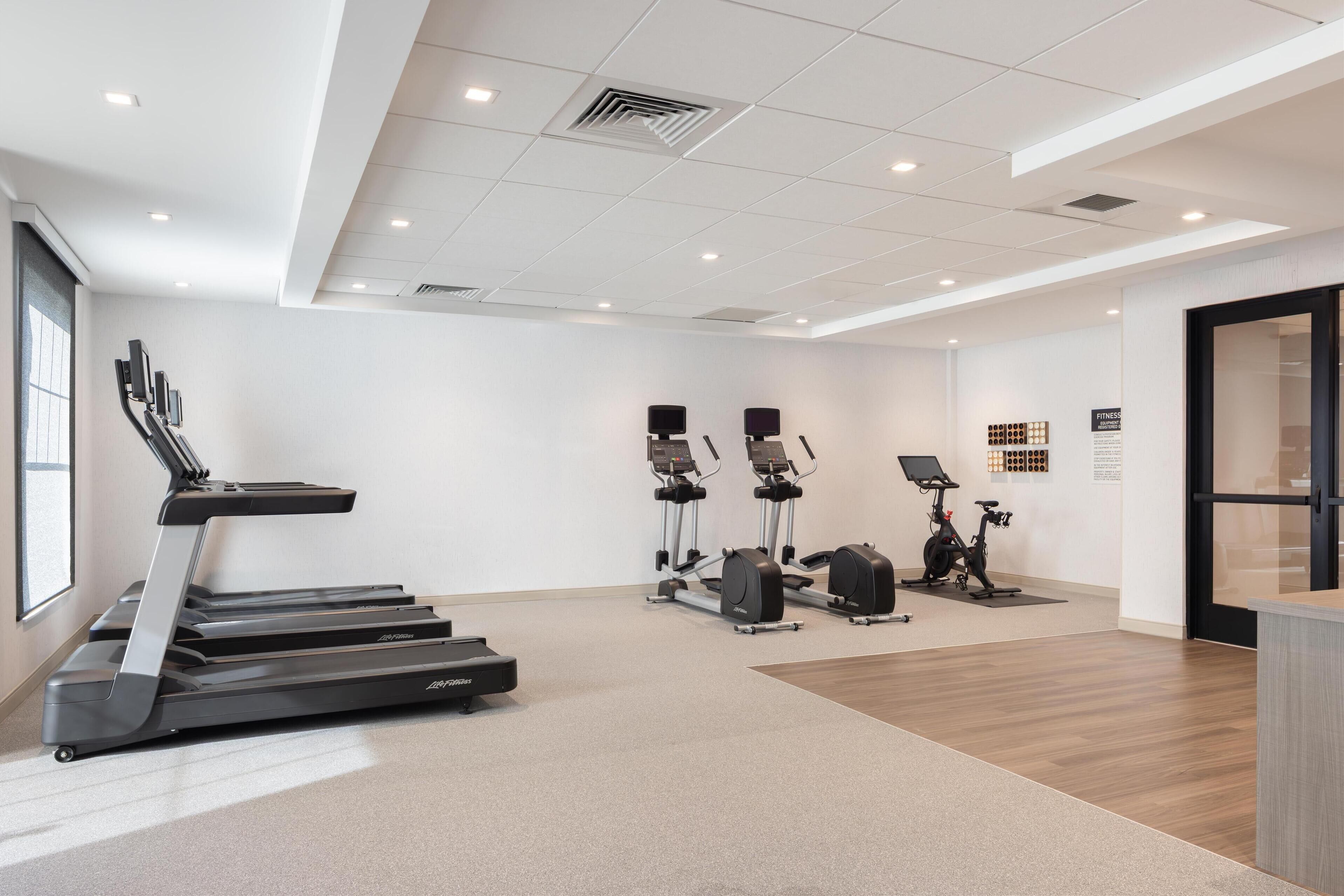 A modern fitness center with treadmills, elliptical machines, and stationary bikes.