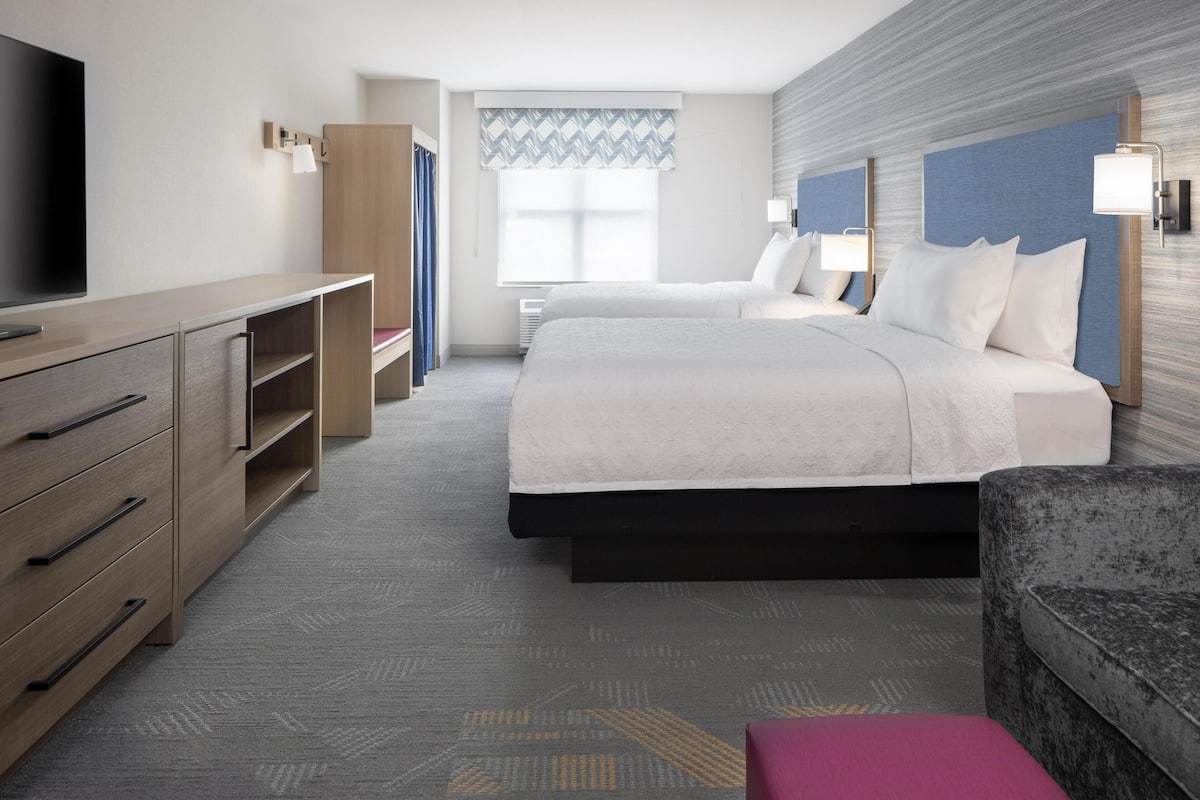 A hotel room with a bed, a TV, a desk, and a wardrobe.