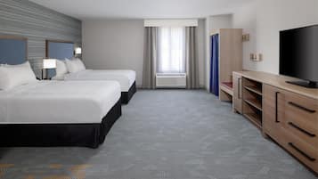 Habitación de hotel con dos camas, televisión, escritorio y un amplio ventanal con cortinas.