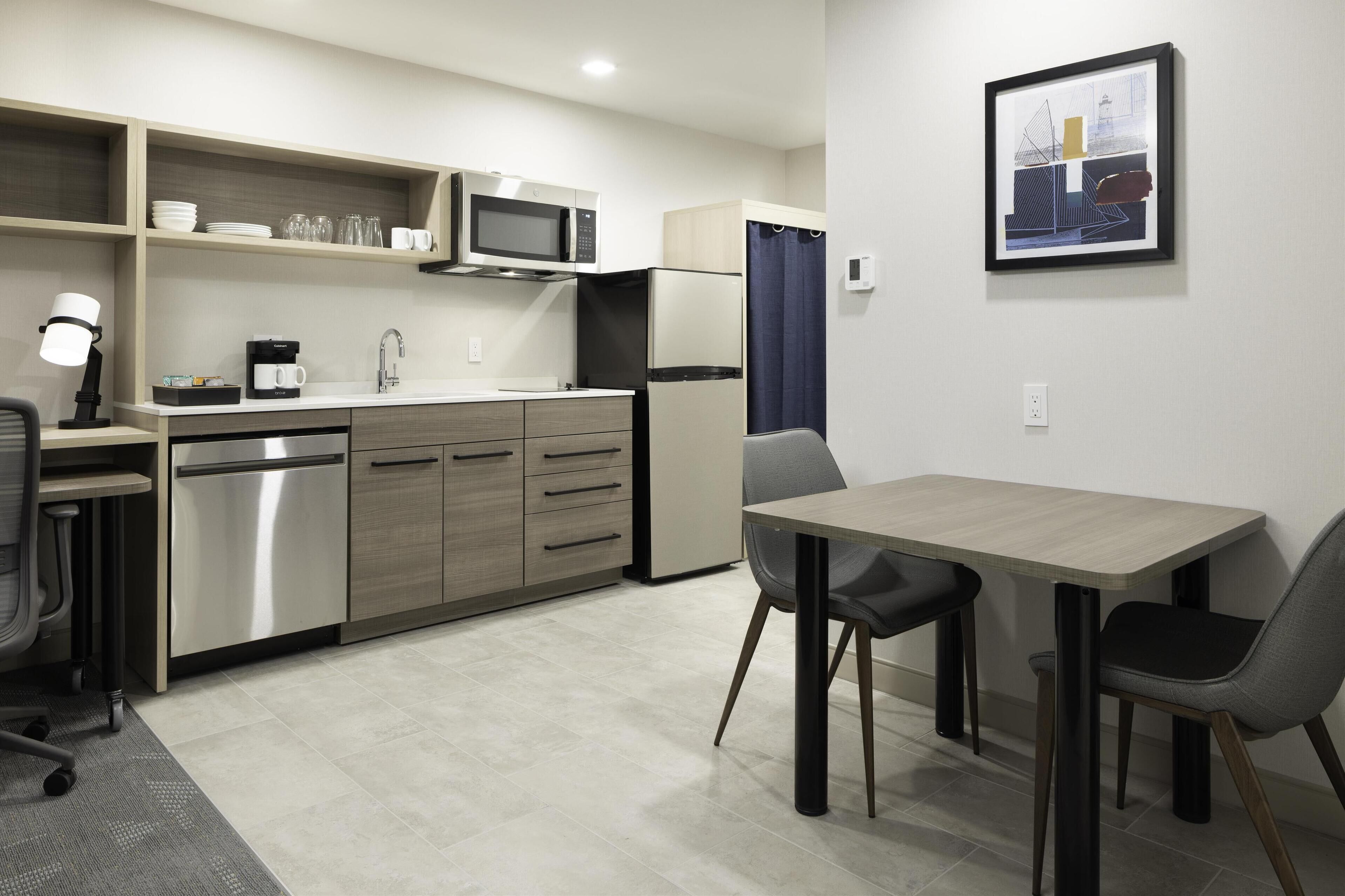 A compact kitchen with a microwave, refrigerator, and a dining area with a table and chairs.