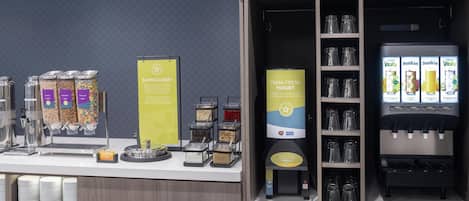 Una barra de desayuno con diversas opciones de alimentos, como cereales, avena y yogur.