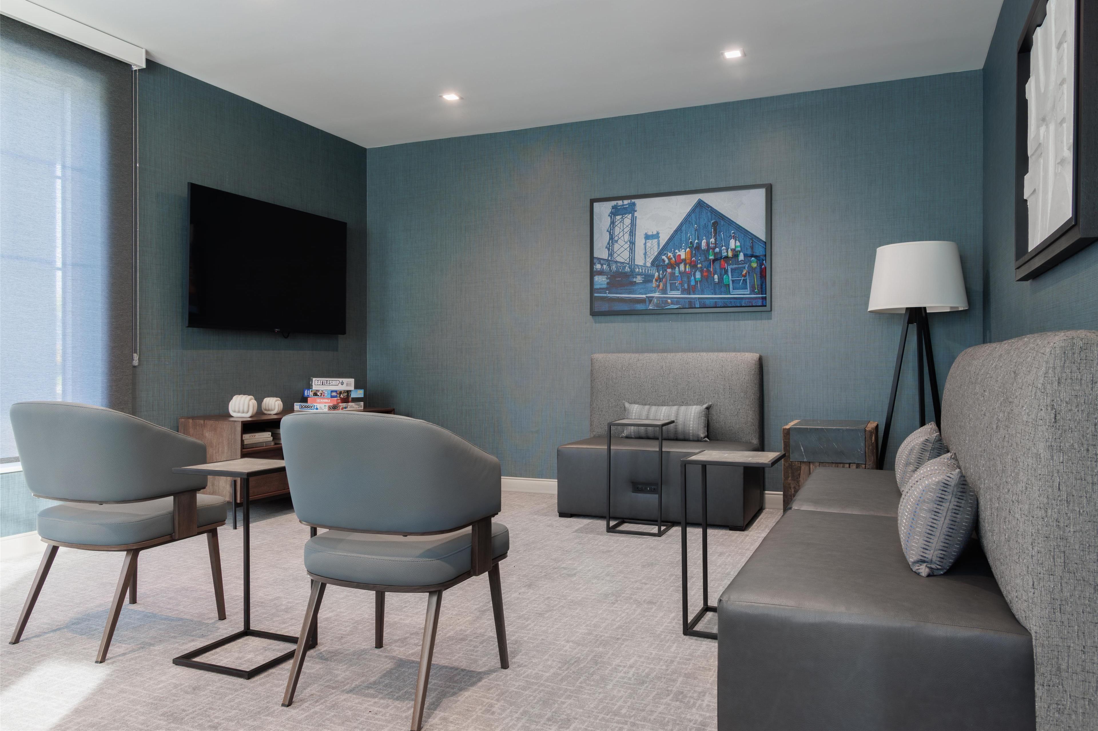 Una sala de estar moderna con un sofá, dos sillones, una mesa de centro y un televisor montado en la pared.