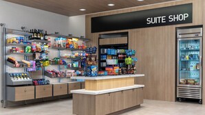A modern suite shop with neatly organized shelves of snacks, beverages, and toiletries.