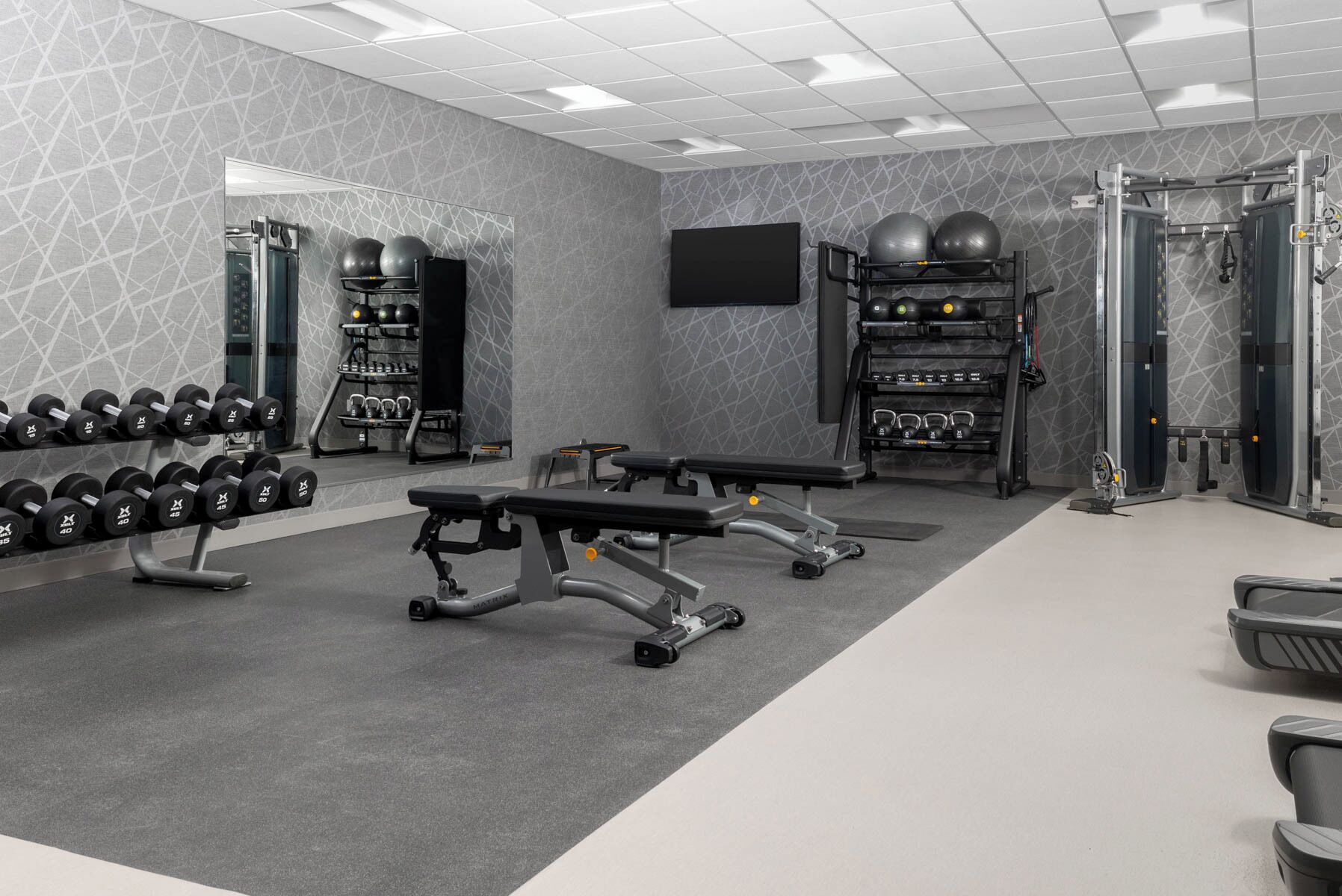 A modern gym with weightlifting equipment, dumbbells, and exercise balls.