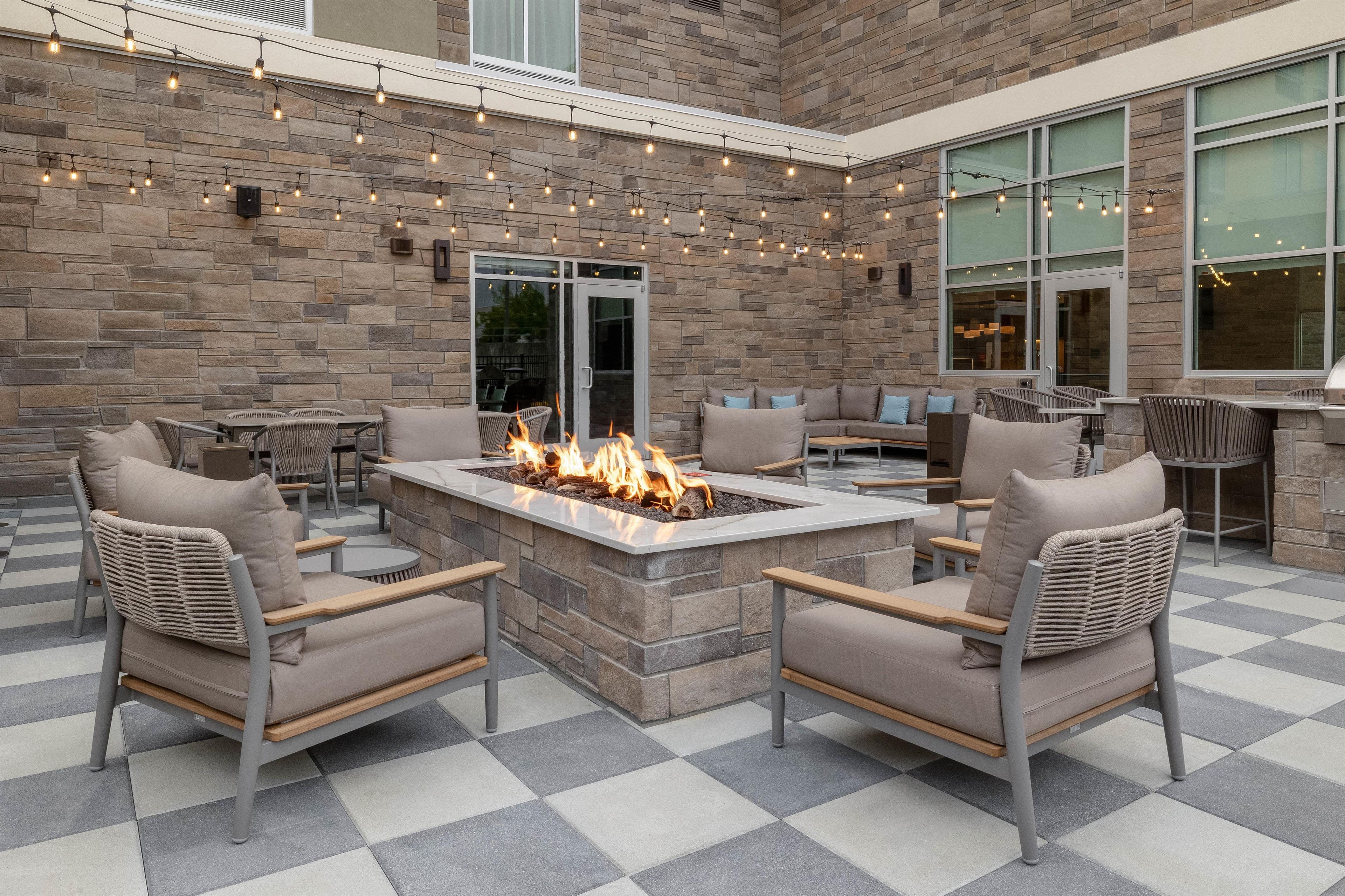 An outdoor patio with stone walls, a fire feature, and multiple seating areas.