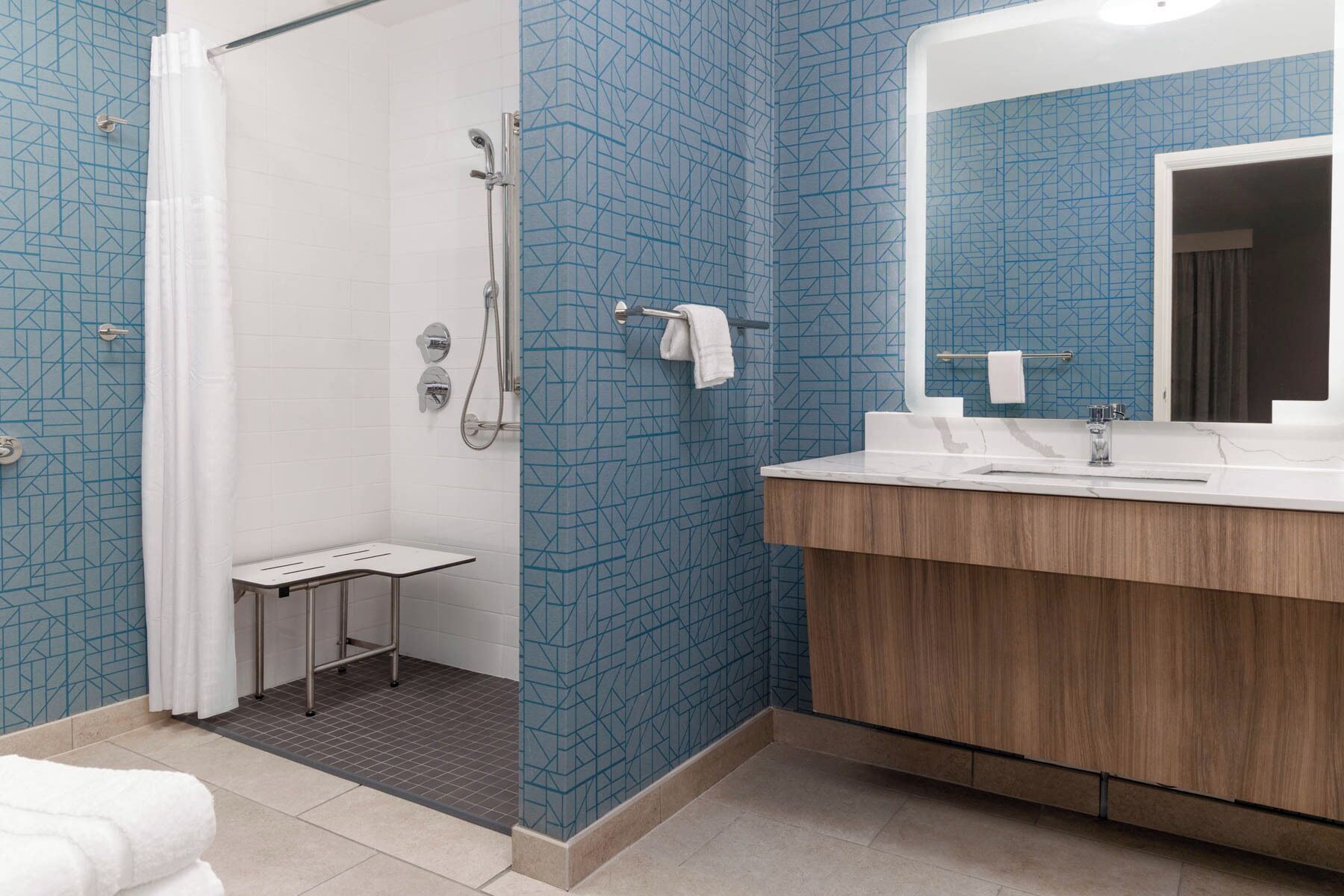 Een badkamer met een douche, wastafel en spiegel.