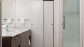 A modern bathroom with a white vanity, a glass shower enclosure, and a door with a handle.