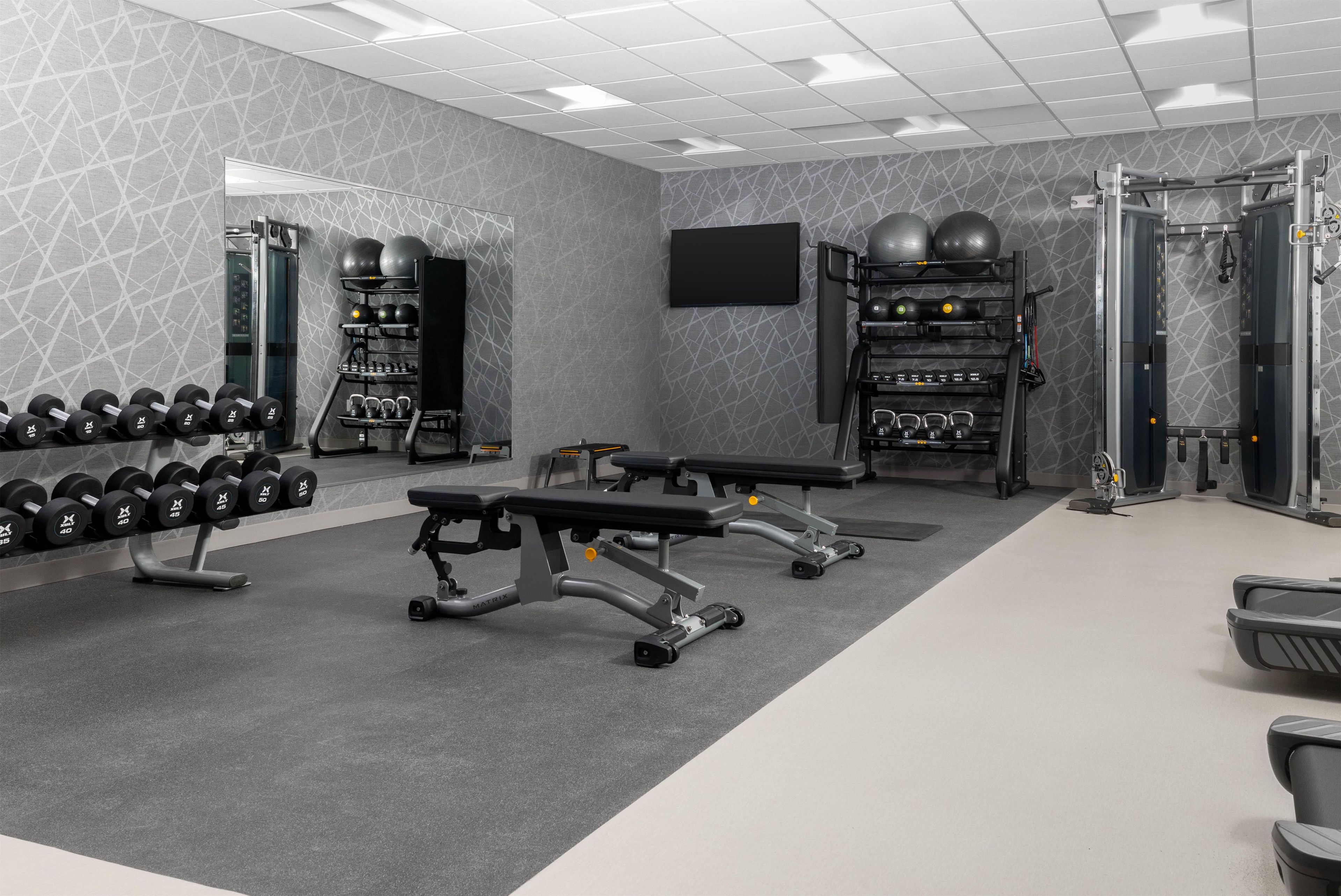 A gym with weightlifting equipment, dumbbells, and exercise machines.