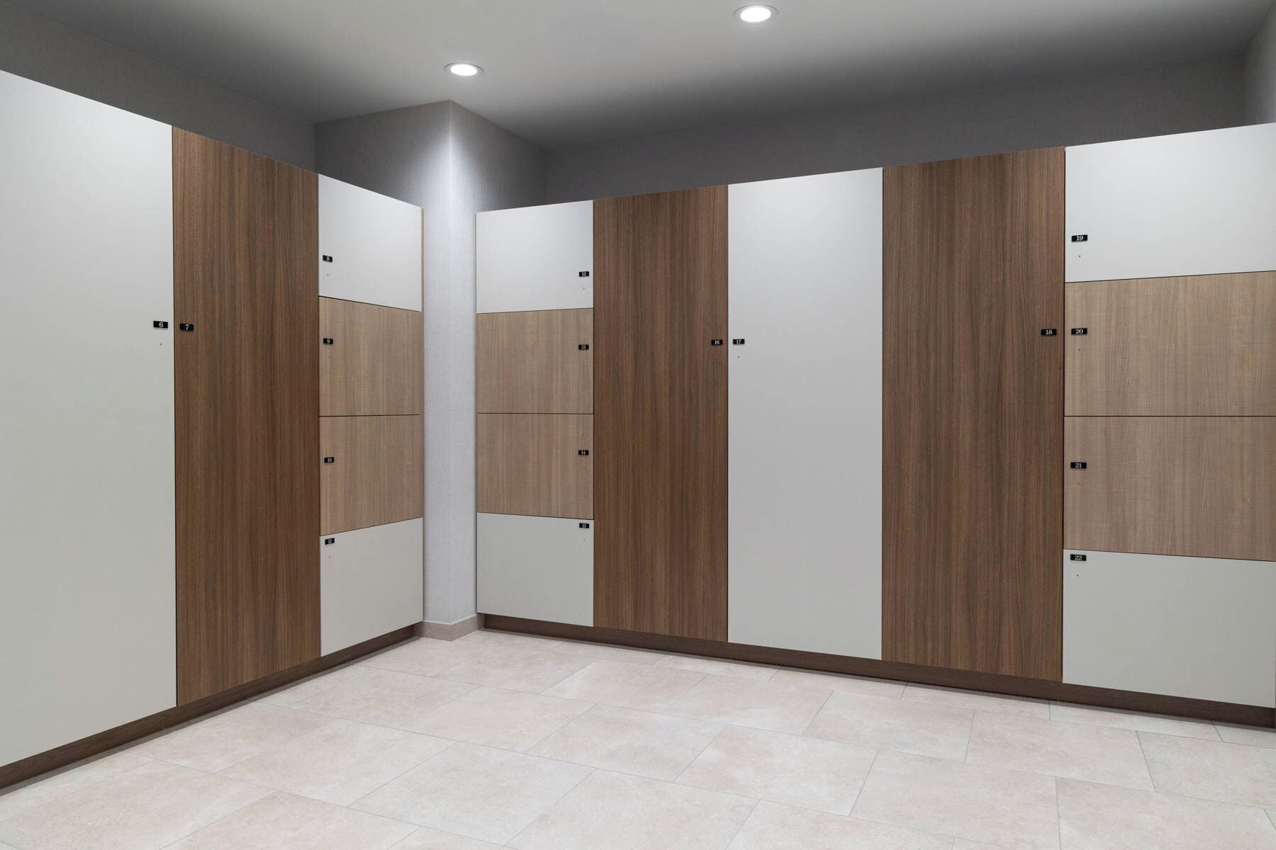 A modern, multi-room hotel suite with a neutral color palette, featuring a combination of wooden and white panel walls, a tiled floor, and a recessed ceiling light.