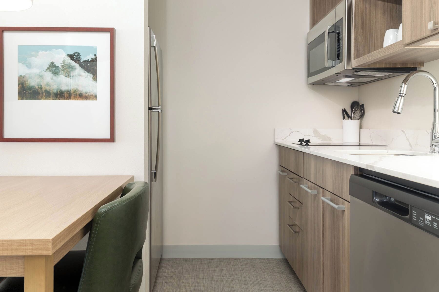 A compact kitchen with a wooden table, a refrigerator, a microwave, and a dishwasher.