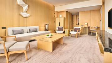 A modern living room with a sofa, chairs, a coffee table, and a kitchen area with a counter and cabinets.