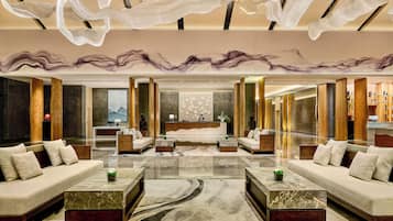 A spacious lobby with a reception desk, sofas, and a large mirror.
