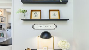 A desk with a lamp, a framed quote, and a small vase with flowers.