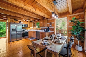 A wooden cabin kitchen with a stainless steel refrigerator, microwave, and dishwasher.