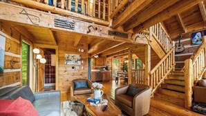 Ein Holzblockhaus-Innenraum mit Essbereich, Sitzgelegenheiten und einer Treppe.