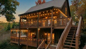 Eine zweistöckige Holzhütte mit Balkon, Treppe und Lichterketten.