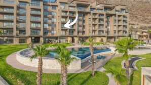 Un hotel moderno de varios pisos, con piscina central y montañas al fondo.