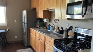 A kitchen with wooden cabinets, stainless steel appliances, a microwave, stove, and a refrigerator.