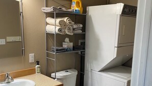 A compact bathroom with a sink, toilet, and a laundry machine.