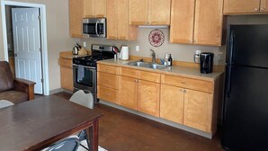 A kitchen with wooden cabinets, a stainless steel stove, a microwave, a refrigerator, and a coffee maker. - Tundra Apt #2-Modern Comfort in the Last Frontier (For families or casual travelers) (Tok)