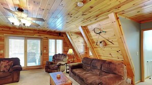 Een knus loft-appartement met schuine plafonds, houten wanden en grote ramen.