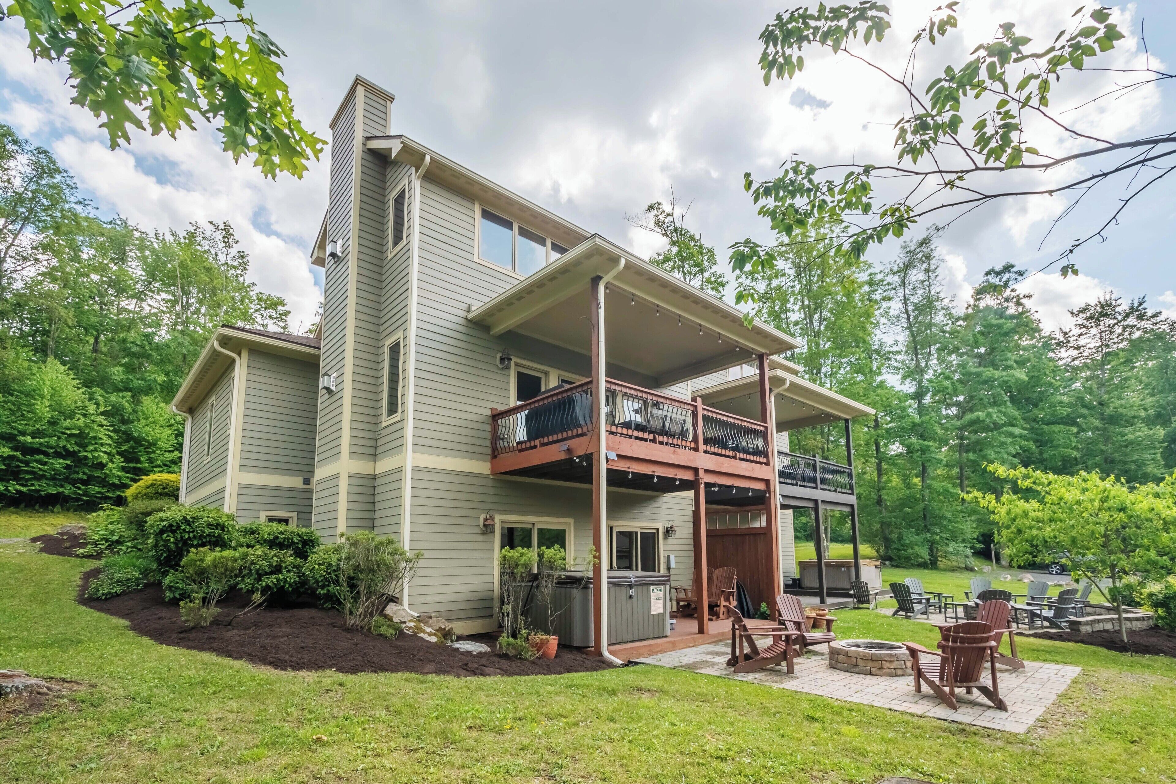 A two-story house with a covered patio, outdoor seating, and a fire pit.