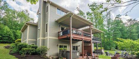 Une maison à deux étages dotée d’un patio couvert, d’un espace salon extérieur et d’un foyer.