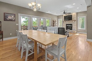A spacious dining area with a wooden table and white chairs, a fireplace, and a television mounted above it. - Gulfway Hideaway by Taylor Made Deep Creek (Oakland)
