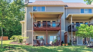 Un bâtiment à deux étages doté d’un balcon au premier étage, d’un patio couvert et d’un petit jardin aménagé avec du mobilier d’extérieur.