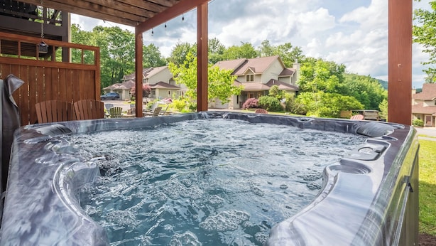 Un bain à remous avec une terrasse en bois et une vue sur les maisons au loin.