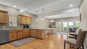 Une cuisine spacieuse dotée de meubles en bois, de plans de travail en granit et de luminaires suspendus.