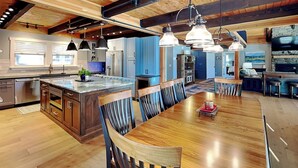 A spacious kitchen with a large island, wooden beams, and pendant lighting. - As You Lake It by Taylor Made Deep Creek (Oakland)