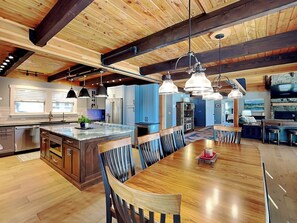 Una cocina amplia con una isla grande, vigas de madera e iluminación colgante.