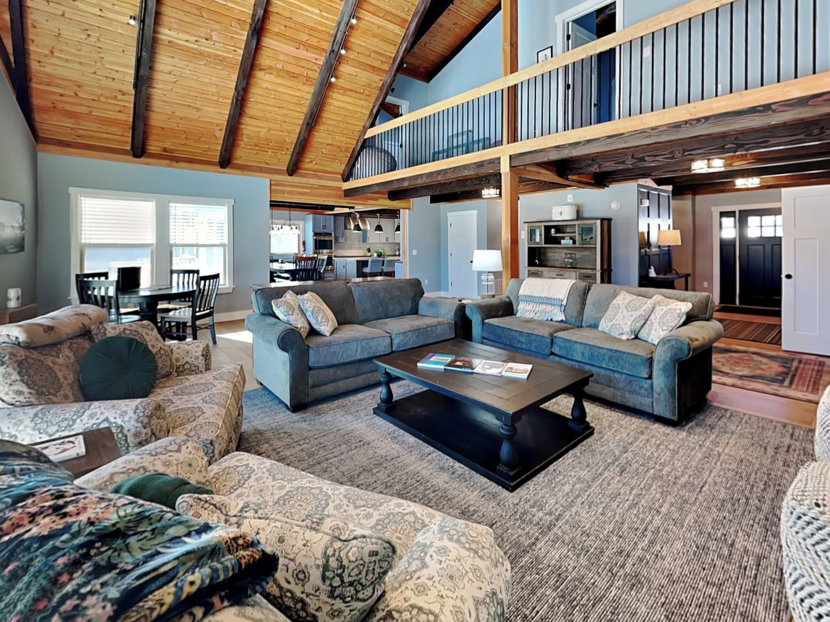 A spacious living area with a high ceiling and exposed beams, a dining area, and a kitchen.