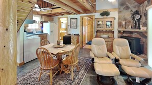 A wooden interior with a dining area, kitchen, and seating with a fireplace.