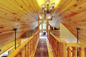 Un interior de madera con un pasillo central, barandillas de madera y un candelabro.