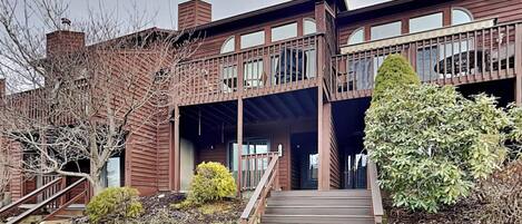 A two-story building with a wooden facade, a covered porch, and a staircase leading to the entrance.