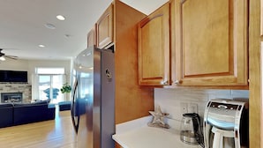 A modern kitchen with wooden cabinets, a stainless steel refrigerator, a coffee maker, and a star-shaped decoration on the countertop. - Dacha Verde by Taylor Made Deep Creek (Swanton)