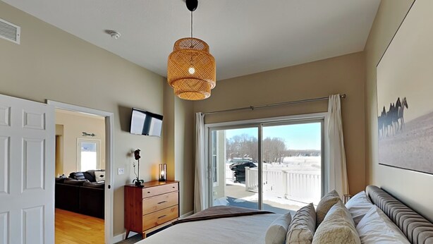 A bedroom with a large bed, a dresser, a television, and a view of the outdoors through a sliding glass door. - Dacha Verde by Taylor Made Deep Creek (Swanton)
