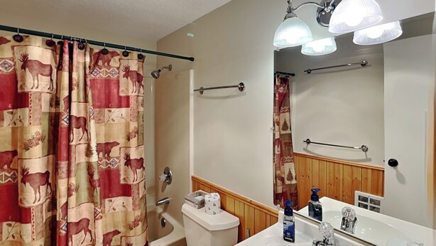 Baño con inodoro, lavamanos y cortina de ducha con estampado de animales.