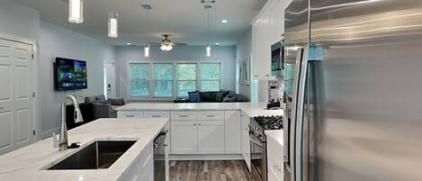 A modern kitchen with white cabinetry, a stainless steel refrigerator, and a central island.