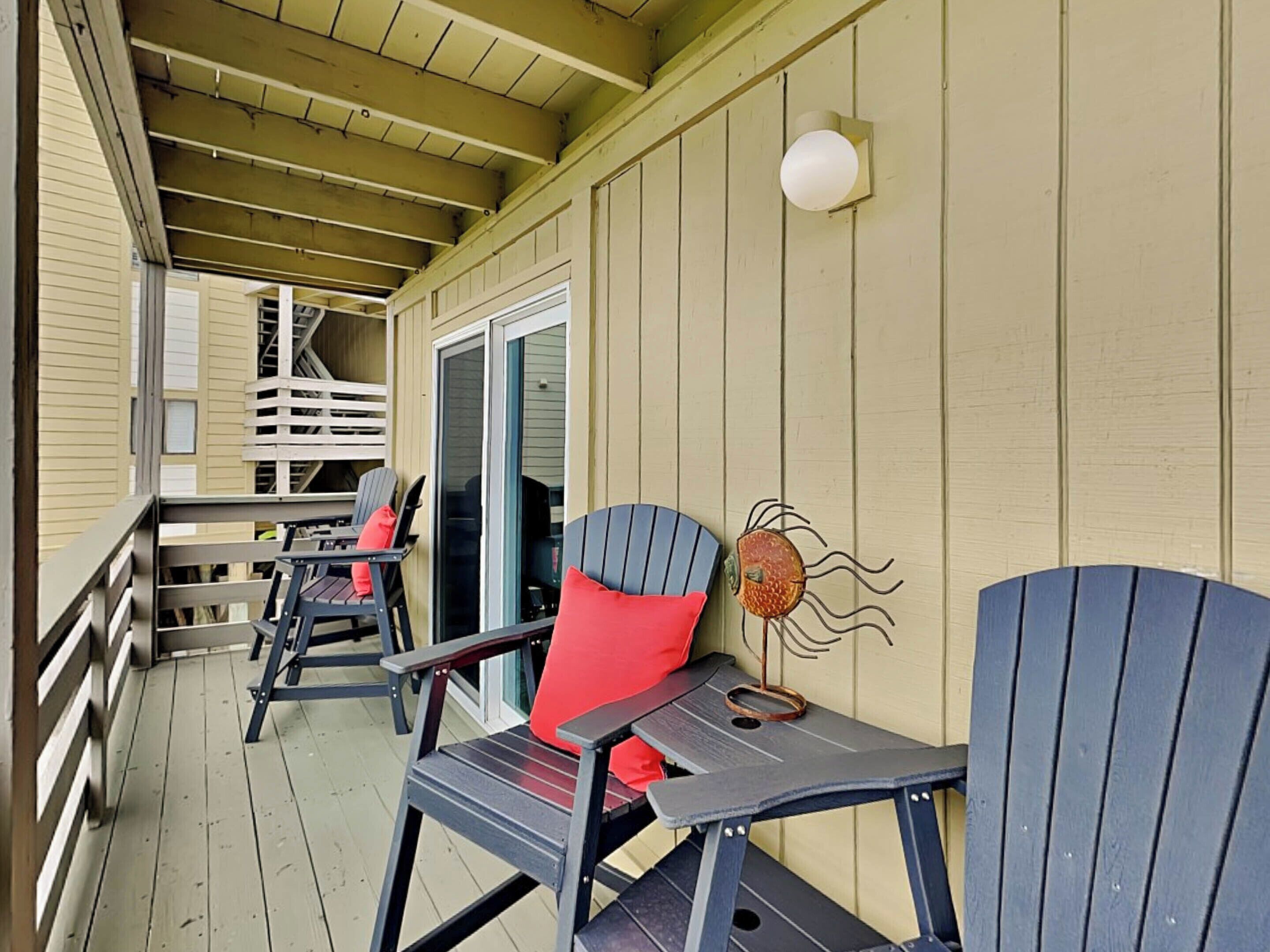 A covered porch with Adirondack chairs and a decorative wall piece.